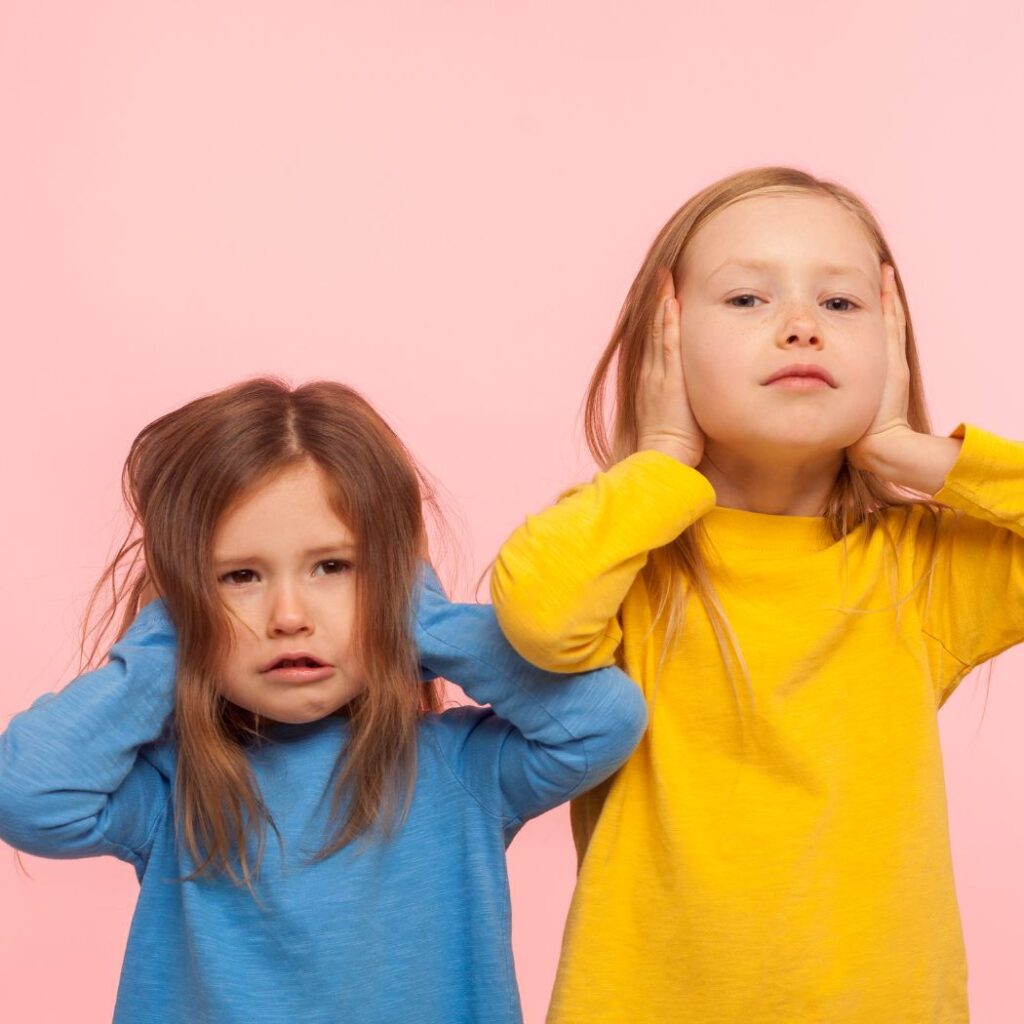 two young girls holding ears