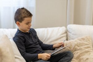 Young boy sitting on a couch using an iPad